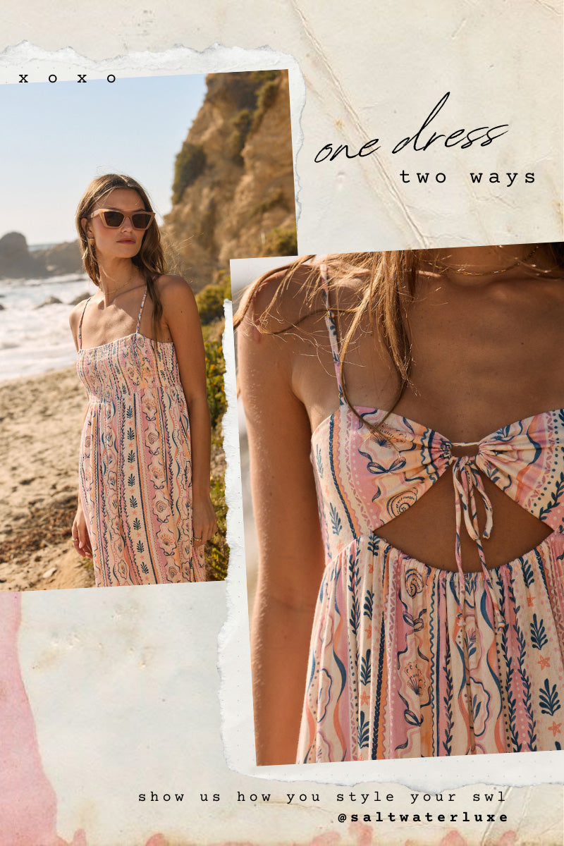 Model wearing the Saltwater Luxe Taytum Maxi Dress in a pink seashell-inspired print styled on a coastal cliffside with reversible two-way neckline detail
