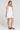 Side angle view of a woman wearing the Saltwater Luxe Adelina Mini Dress in White on a neutral background