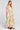 Side angle view of a woman wearing the Saltwater Luxe  Arosa Midi Dress in Fawn on a neutral background