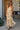 Back view of a woman wearing the Saltwater Luxe  Arosa Midi Dress in Fawn in front of a house