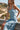 Front view of a woman wearing the Saltwater Luxe Elison Dusty Blue Midi Dress seated overlooking a beach