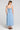 Back view of a woman wearing the Saltwater Luxe Elison Dusty Blue Midi Dress on a neutral background