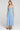 Side angle view of a woman wearing the Saltwater Luxe Elison Dusty Blue Midi Dress on a neutral background