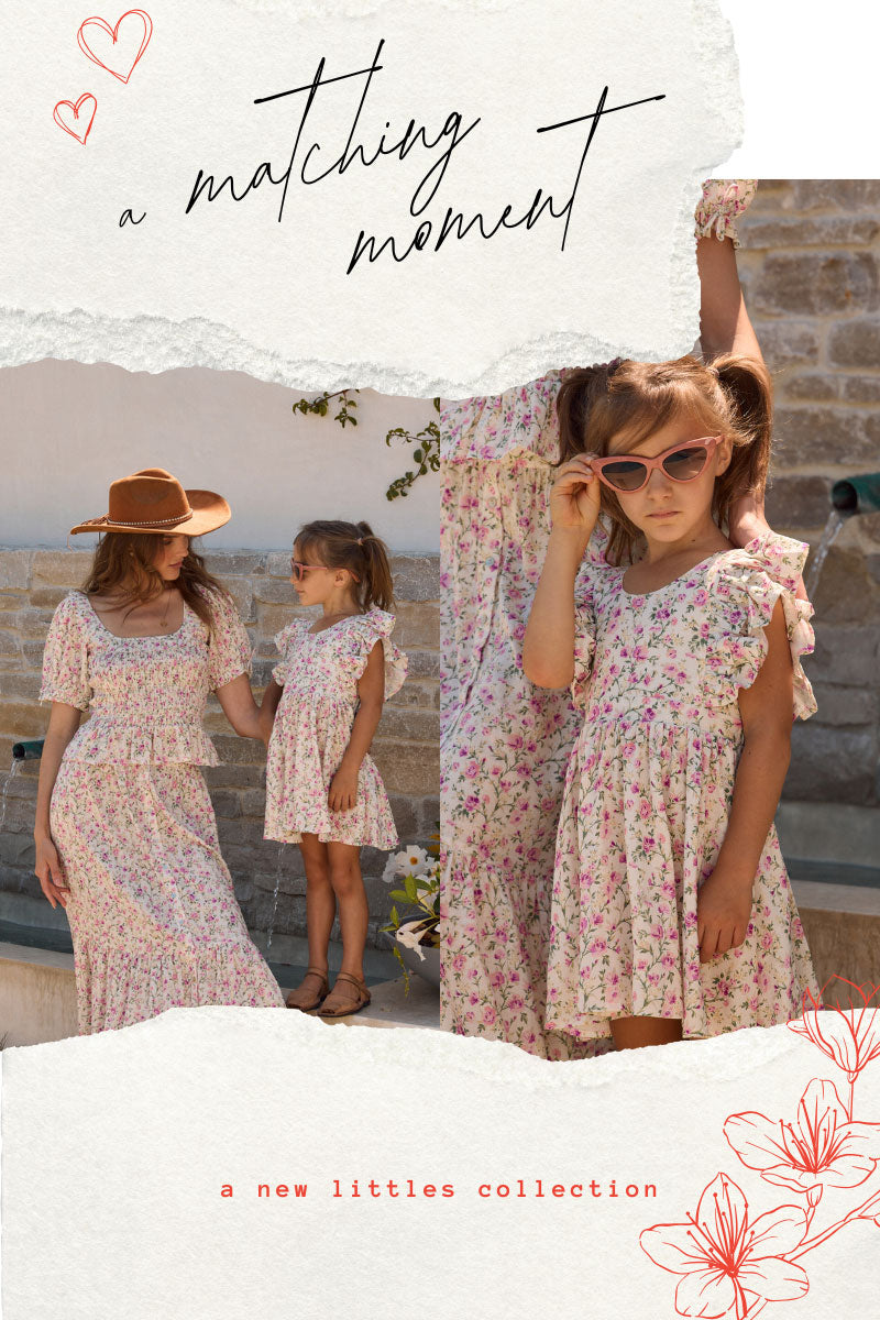 Mother and daughter in matching Saltwater Luxe floral outfits standing outdoors with a decorative banner