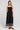 Front view of a woman wearing the Saltwater Luxe Jackstin Black Midi Dress on a neutral background