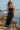 Front view of a woman wearing the Saltwater Luxe Jackstin Black Midi Dress on the beach