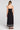 Back view of a woman wearing the Saltwater Luxe Jackstin Black Midi Dress on a neutral background