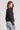 Back view of a woman wearing the Saltwater Luxe Long Sleeve Black Cardigan on a neutral background