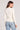 Back view of a woman wearing the Saltwater Luxe Long Sleeve Ecru Cardigan on a neutral background