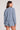 Back view of a woman wearing the Saltwater Luxe Long Sleeve Worn Blue Pullover on a neutral background