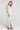 Side angle view of a woman wearing the Saltwater Luxe Medina Midi Dress in Pearl on a neutral background