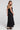 Back view of a woman wearing the Saltwater Luxe Melia Black Maxi Dress on a neutral background