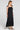 Side angle view of a woman wearing the Saltwater Luxe Melia Black Maxi Dress on a neutral background