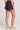 Back view of a woman wearing the Saltwater Luxe Pull On Black Shorts on a neutral background