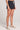 Side angle view of a woman wearing the Saltwater Luxe Pull On Black Shorts on a neutral background