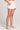 Side angle view of a woman wearing the Saltwater Luxe Pull On Ecru Shorts on a neutral background
