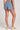 Back view of a woman wearing the Saltwater Luxe Pull On Worn Blue Shorts on a neutral background