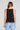 Back view of a woman wearing the Saltwater Luxe Quinley Black Tank on a neutral background