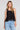 Front view of a woman wearing the Saltwater Luxe Quinley Black Tank on a neutral background
