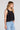Side angle view of a woman wearing the Saltwater Luxe Quinley Black Tank on a neutral background