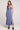 Full body view of woman wearing the Saltwater Luxe blue Cannan Midi Dress with a slit on a plain background
