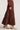 Side view of woman wearing the Saltwater Luxe Jaycee Midi Skirt in Chocolate Brown on a white background