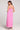 Back full body view of a woman wearing the Saltwater Luxe pink Hayley Midi Dress with a slit on a plain background