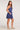 Side profile of woman modeling the Saltwater Luxe Arwen Mini Dress in Blue in studio lighting on a white backdrop