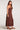 Side view of woman wearing the Saltwater Luxe chocolate brown Romie Midi Dress with brown shoes on a plain background
