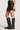 Side view of woman wearing the Saltwater Luxe black Zerra Mini Skirt with black knee-high boots on a plain background