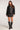 Full body view of woman wearing the Saltwater Luxe Vespera black faux leather jacket with knee-high boots and the matching Zerra Mini Skirt on a plain background
