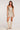 Full body front view of woman wearing the Saltwater Luxe Cassey Mini Dress in champagne gold with faded star prints and a subtle sparkle finish paired with beige knee-high boots on a white background
