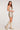 Full body side view of woman wearing the Saltwater Luxe Cassey Mini Dress in champagne gold featuring faded star prints and a soft sparkle finish with beige knee-high boots on a white background