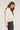 Side view of woman wearing the Saltwater Luxe Kaius Sweater in cream knit with dark jeans on a plain background
