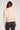 Back view of woman wearing the Saltwater Luxe Kaius Sweater in cream knit with dark jeans on a plain background