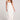 Woman wearing the Saltwater Luxe Adele Midi Dress in white with decorative straps on a plain background