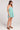 Side full body view of a woman wearing the green and white striped Saltwater Luxe Genevieve Mini Dress on a plain background
