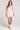 Front view of a woman wearing the Saltwater Luxe floral Enya Salt Mini Dress and white boots on a plain background
