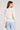Back view of woman wearing the Saltwater Luxe Amorette salt white sweater and light blue jeans on a gray background