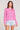 Front view of a woman wearing the Saltwater Luxe pink Amorette Magnolia Sweater and denim shorts on a plain background