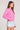 Side view of a woman wearing the Saltwater Luxe pink Amorette Magnolia Sweater and denim shorts on a plain background