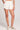 Front view of a woman wearing the Saltwater Luxe Arabella salt white shorts on a plain background
