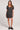Front view of a woman wearing the Saltwater Luxe black floral Cecillia Mini Dress with black shoes on a white background