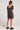 Back view of a woman wearing the Saltwater Luxe black floral Cecillia Mini Dress with black shoes on a white background