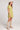 Side view of a woman wearing the Saltwater Luxe green Eldoris Willow Mini Dress with beige boots and a white hat on a plain background