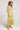 Side view of woman wearing the Saltwater Luxe green Anaya Willow Midi Dress and straw hat on a white background