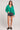 Full body view of the Saltwater Luxe Ellyn Sweater green cardigan shown from the front layered over a black top with denim shorts against a plain background