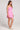 Side view of a woman wearing the Saltwater Luxe pink Deliah Dahlia Mini Dress on a white background