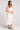 Side view of a woman wearing the Saltwater Luxe Elowena Salt White Midi Dress on a plain background