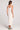 Back view of a woman wearing the Saltwater Luxe Elowena Salt White Midi Dress on a plain background